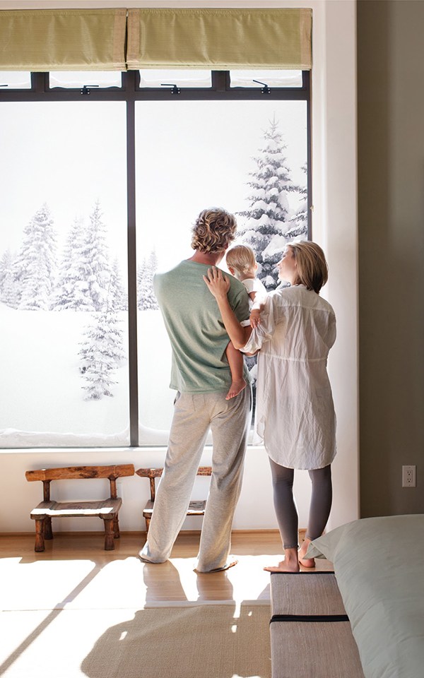 Couple and baby son looking out window with snow outside
